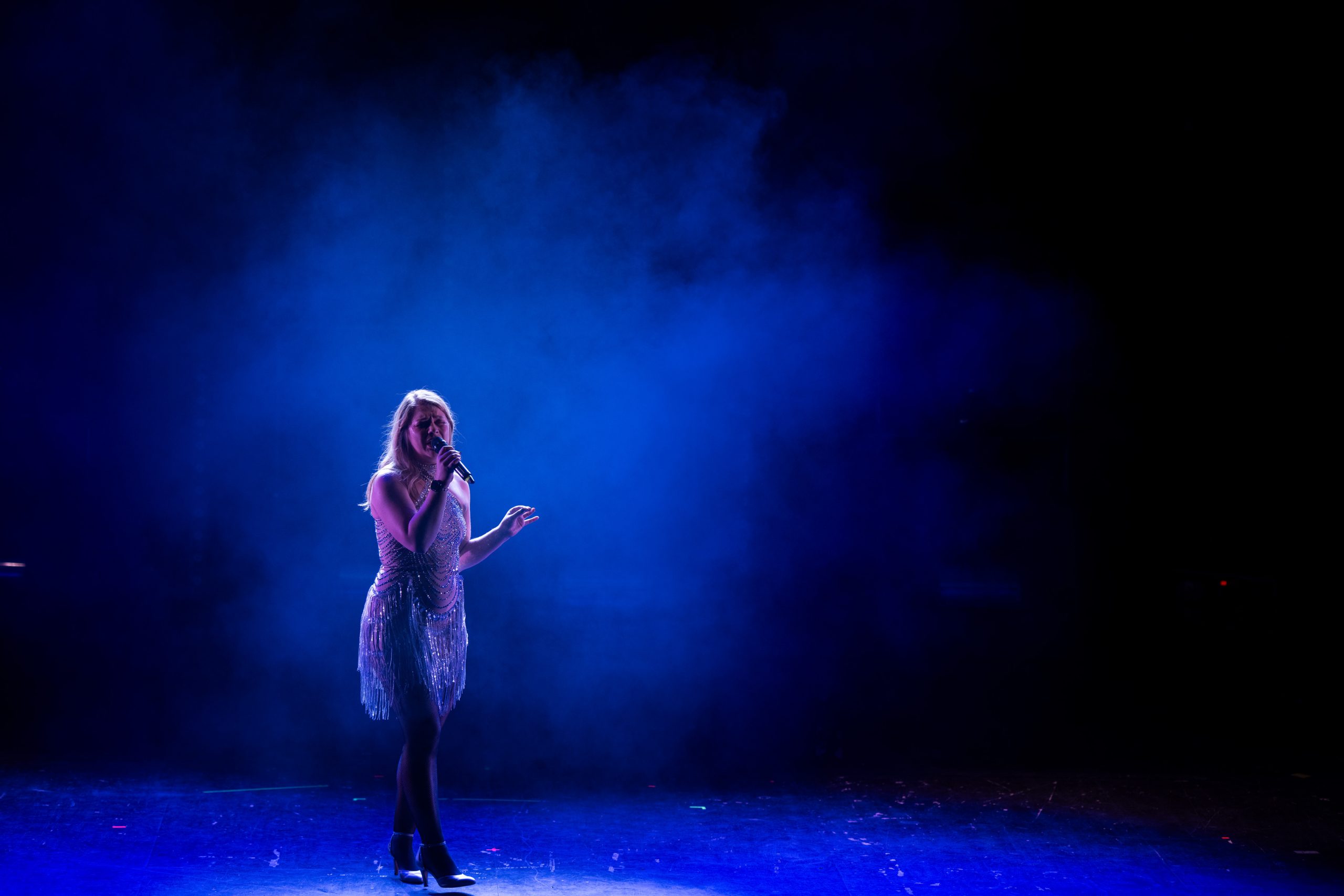 Kvinna som sjunger på scen med blå rök