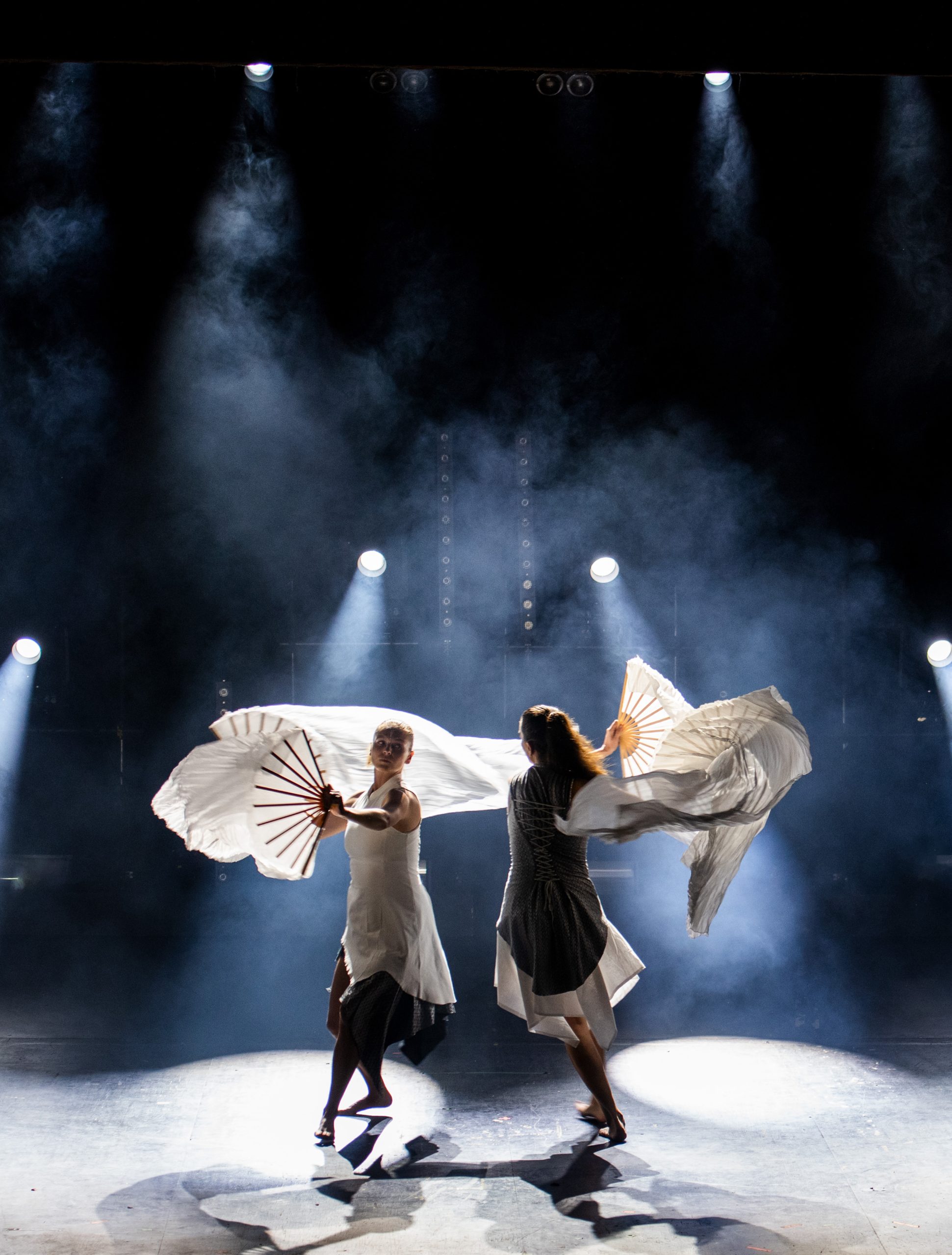 Cirkusartister på scen med vita skynken och fjädrar